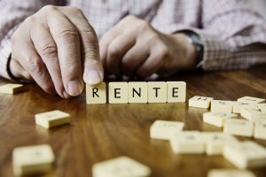 Senior legt mit Buchstaben das Wort Rente